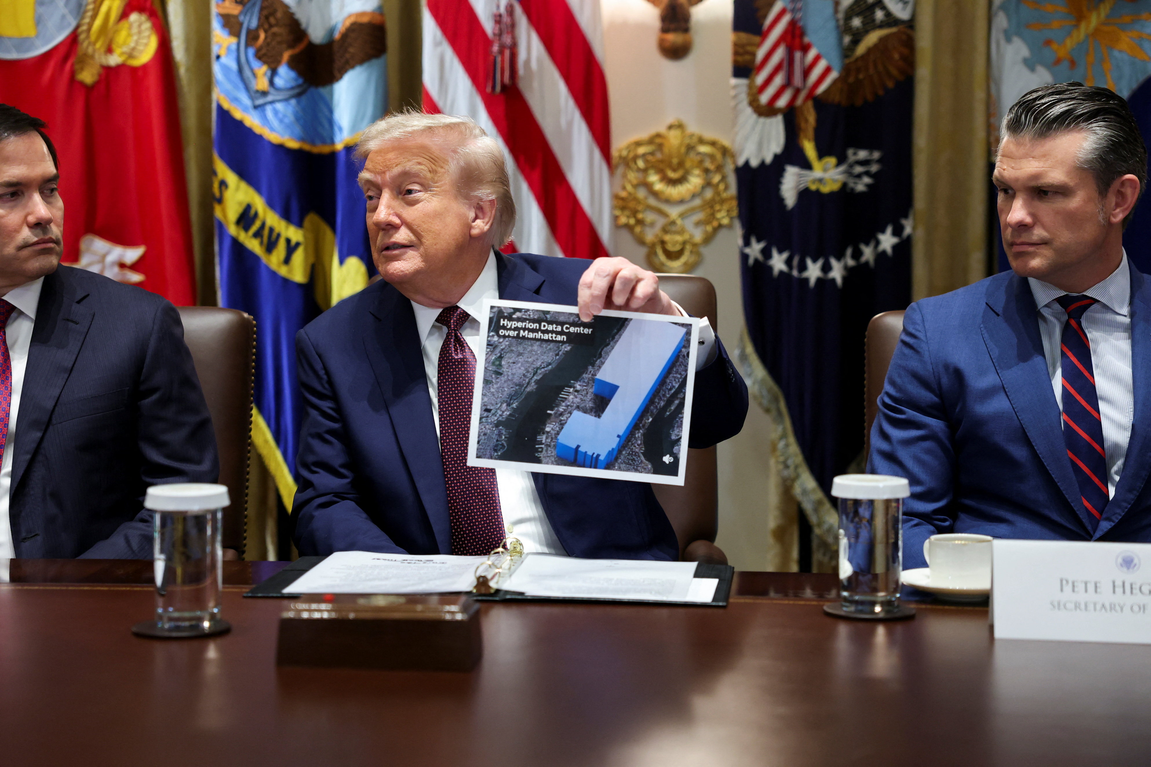 President Trump holding a document depicting the "Hyperion Data Centre over Manhattan" during a cabinet meeting, flanked by Marco Rubio and Pete Hegseth.