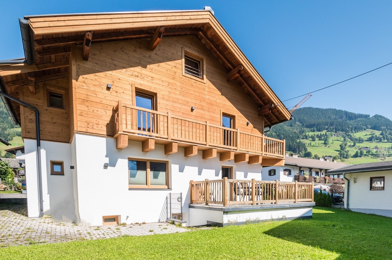 A renovated three-bedroom chalet with a balcony, patio, and a view of green mountains.