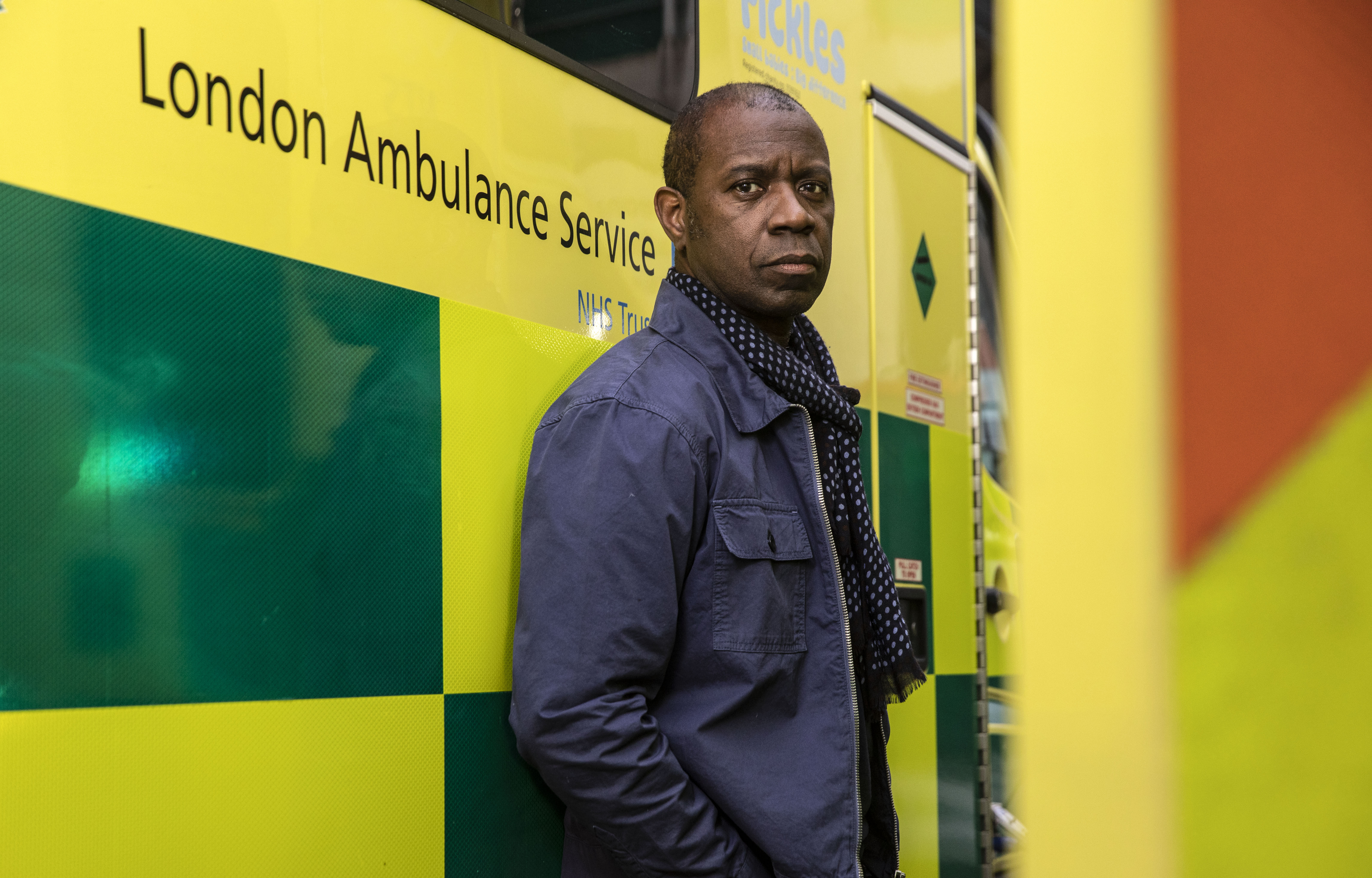 Clive Myrie standing outside the Royal London hospital, next to an ambulance.