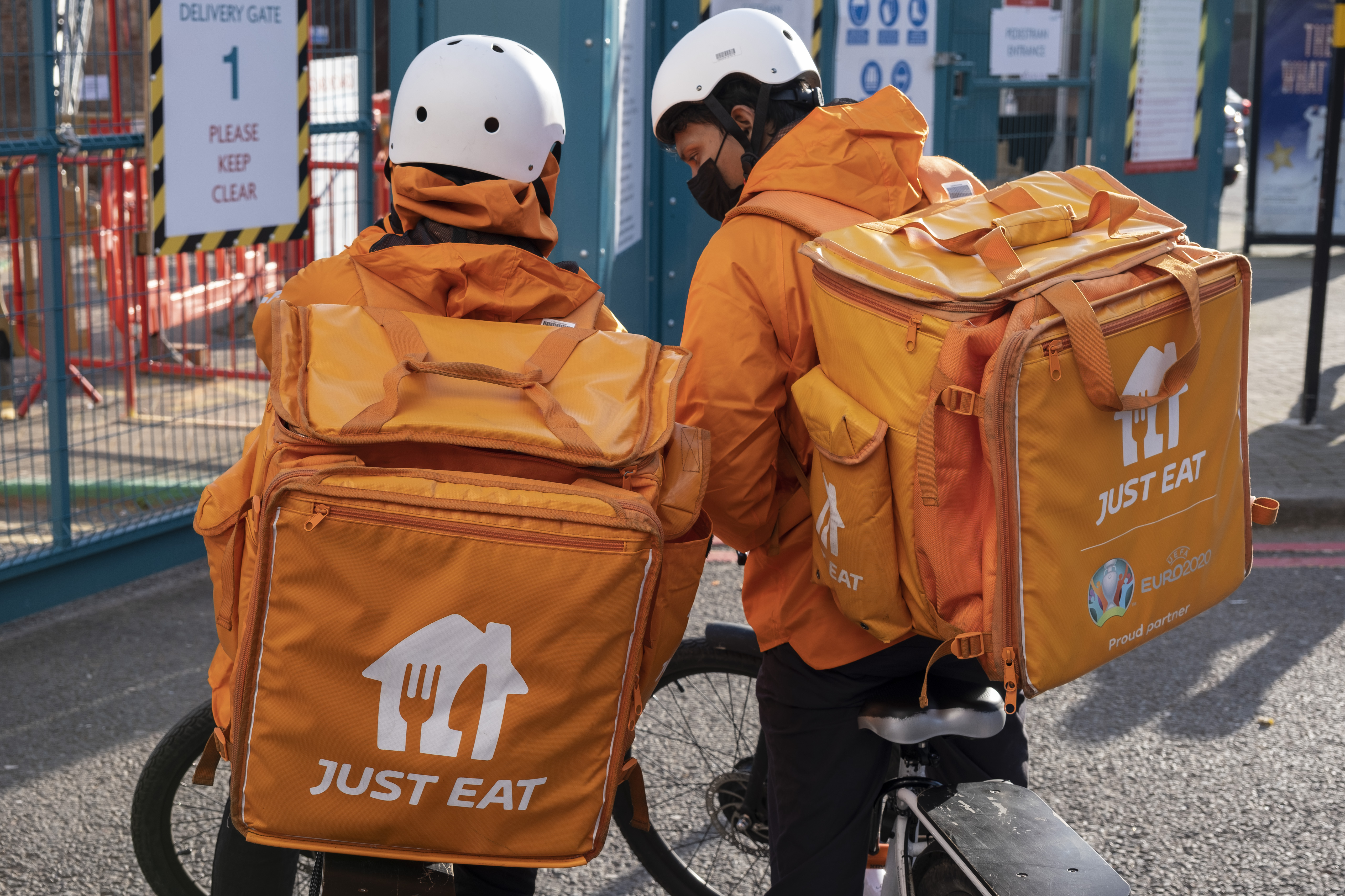Two Just Eat couriers on bicycles with delivery bags.