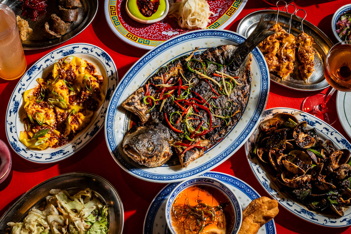 a spread of cantonese style dishes, with a whole fish dish in the middle