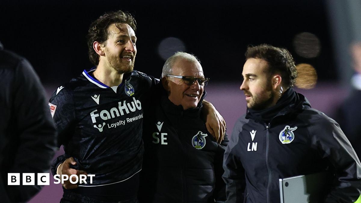 Tom Lockyer (left) smiles as he walks with his arm around the shoulders of Steve Evans (middle) at full-time of a match