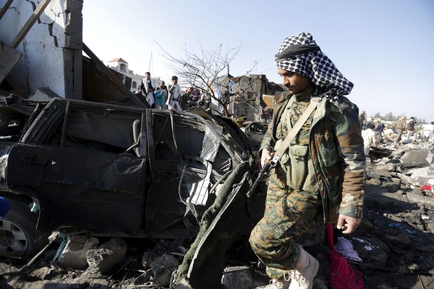 A Houthi fighter walks at the site of an air strike at a residential area near Sanaa Airport on March 26, 2015.