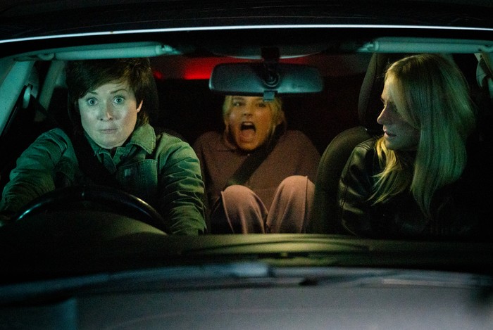 Becky, driving a car, looks shocked as Lisa stares at her in the passenger seat and Betsy screams from behind in a scene from Corriedale