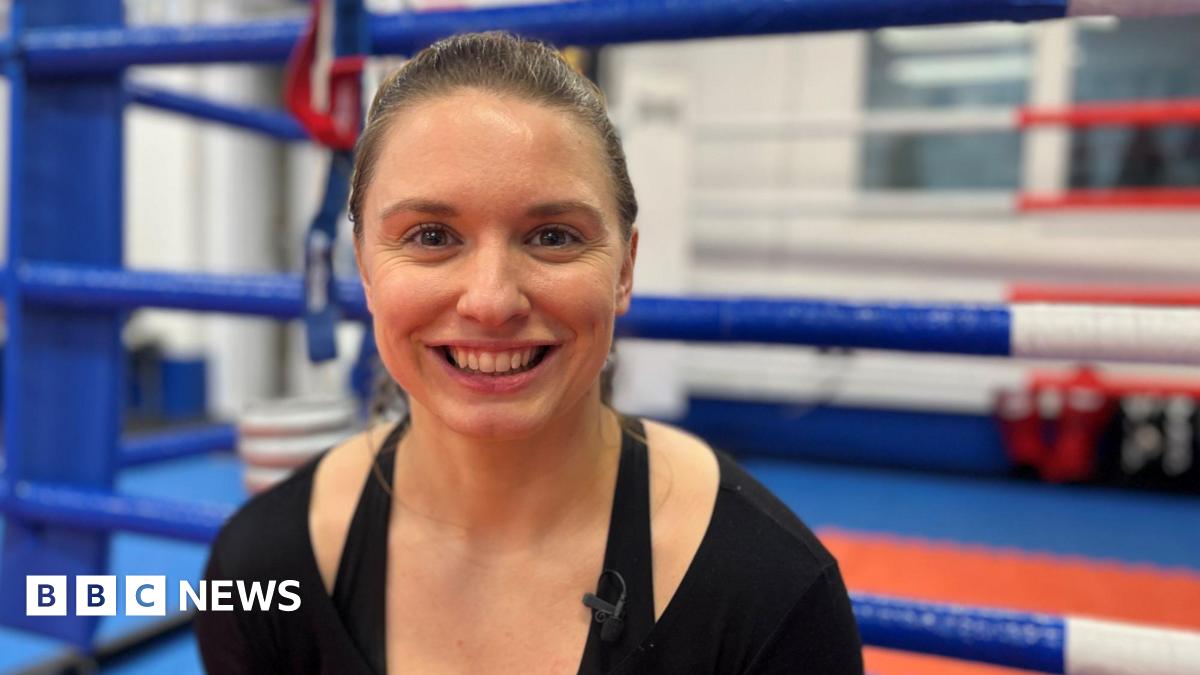 Kat Samuelson pictured at the Rittijak Gym in Swanscombe. Kat is wearing a black top and is smiling to camera. She is sat outside a boxing ring at the gym.