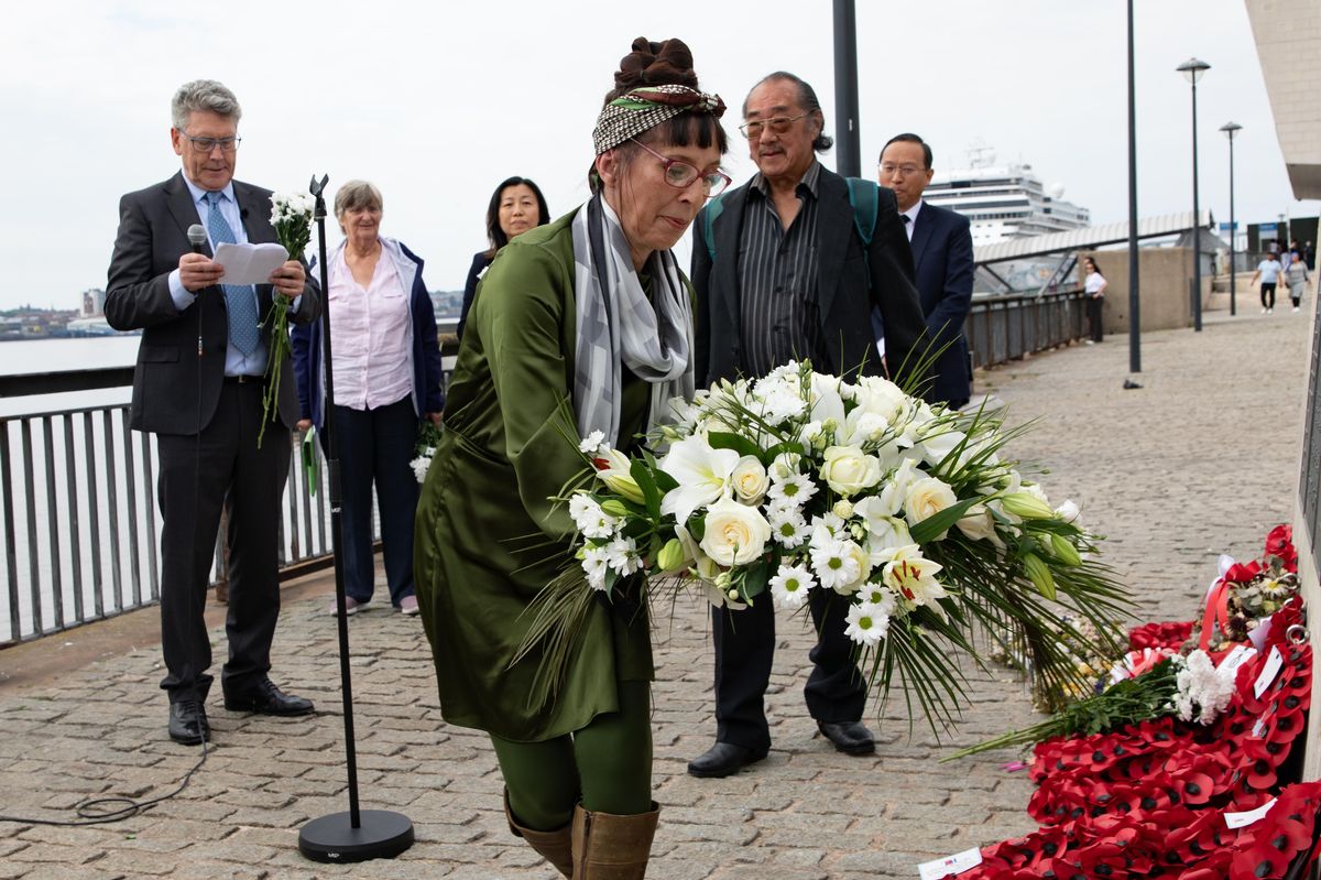 Kellie-Ann Flower lays a bouquet in memory of her grandad at the memorial for the deported seamen at the Pier Head