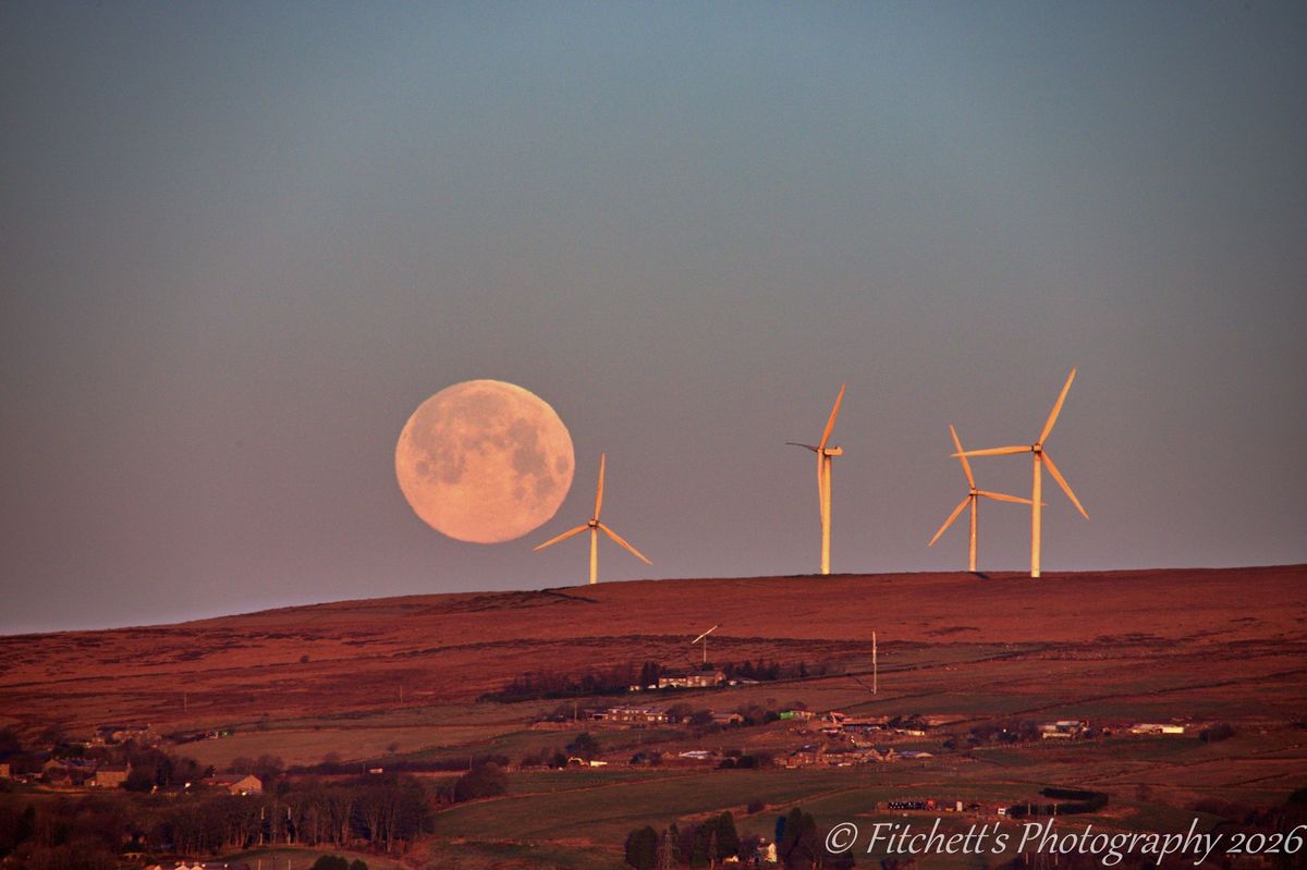 The setting Wolf Moon over Scout Moor, Rochdale, on a freezing morning, from the bridge above the A627M.