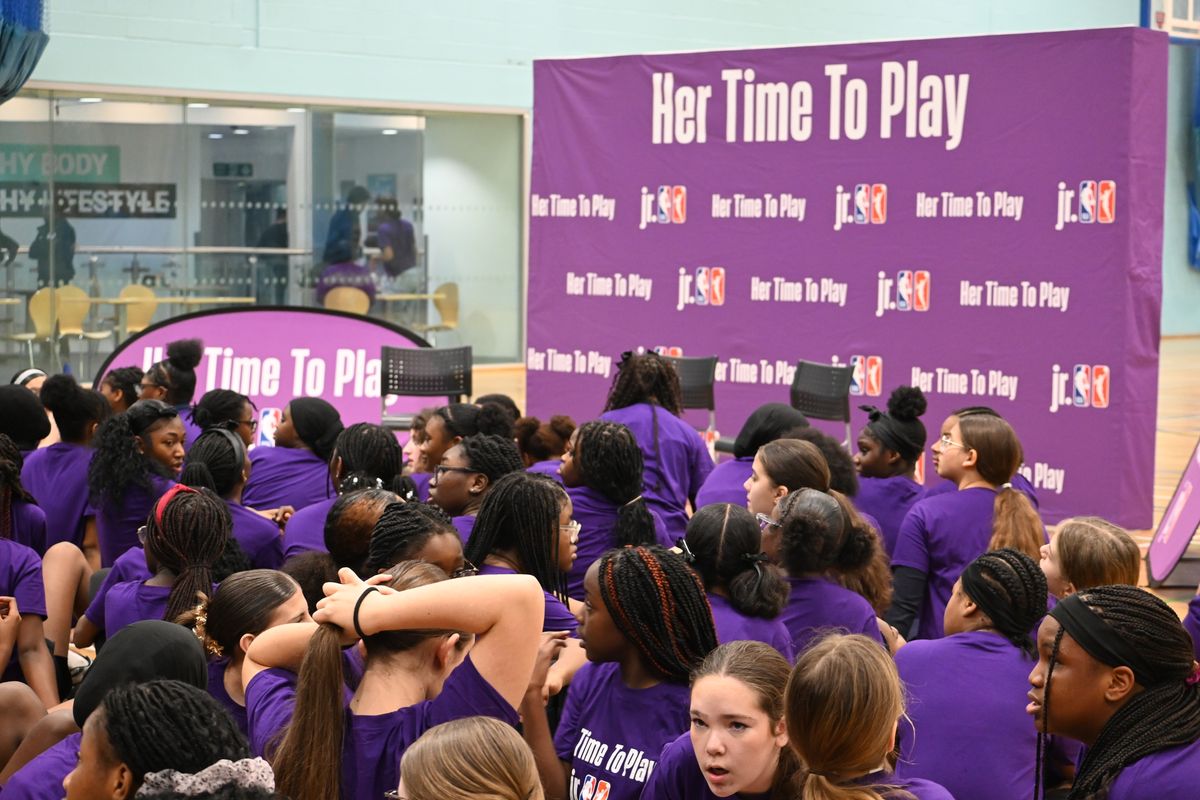 Girls crowded around a board promoting the 'Her Time To Play' sessions