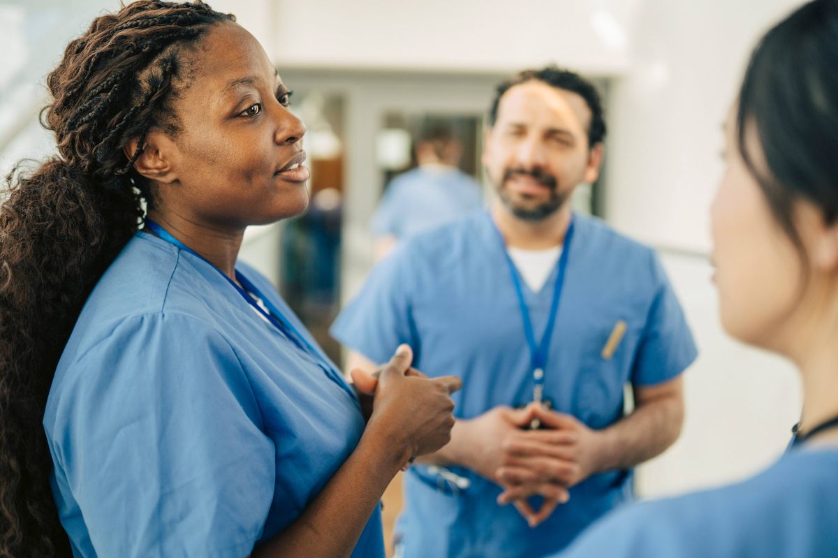 Female nurse communicating with coworker in meeting at hospital