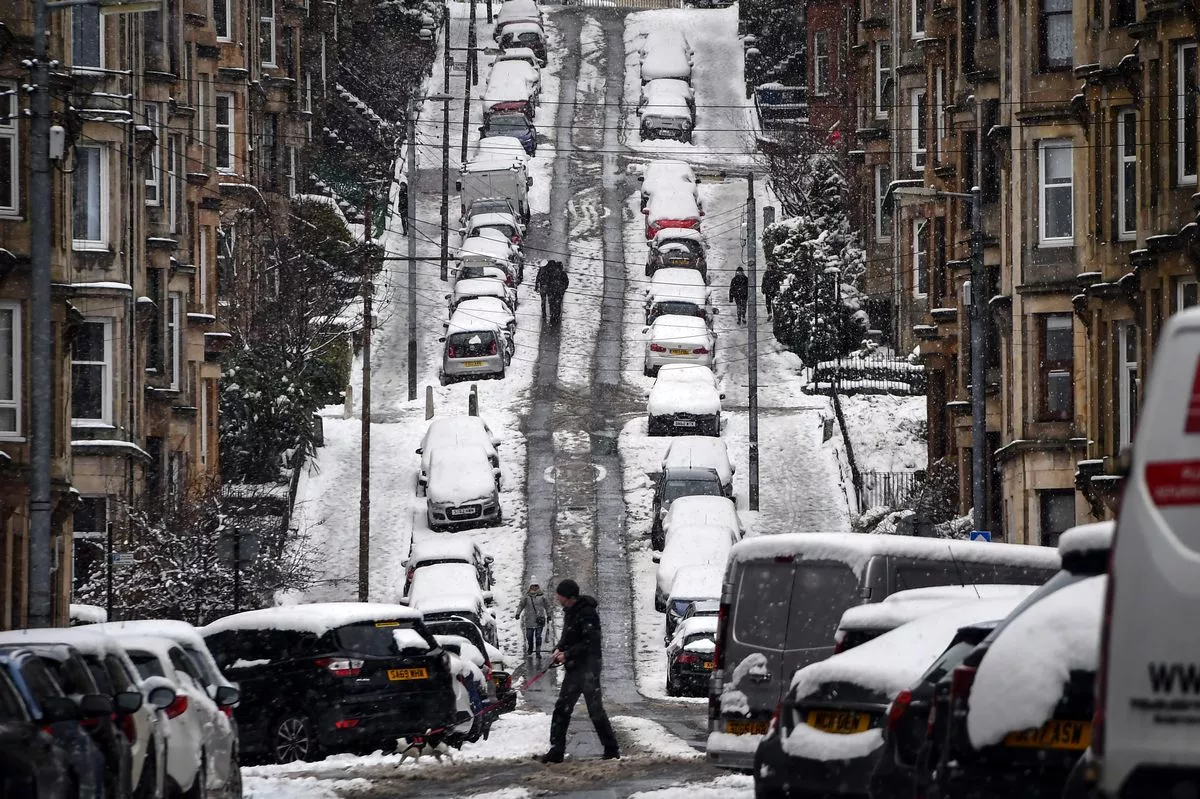 People walk up Gardner Street in Glasgow on February 9, 2021 as snow blankets the city