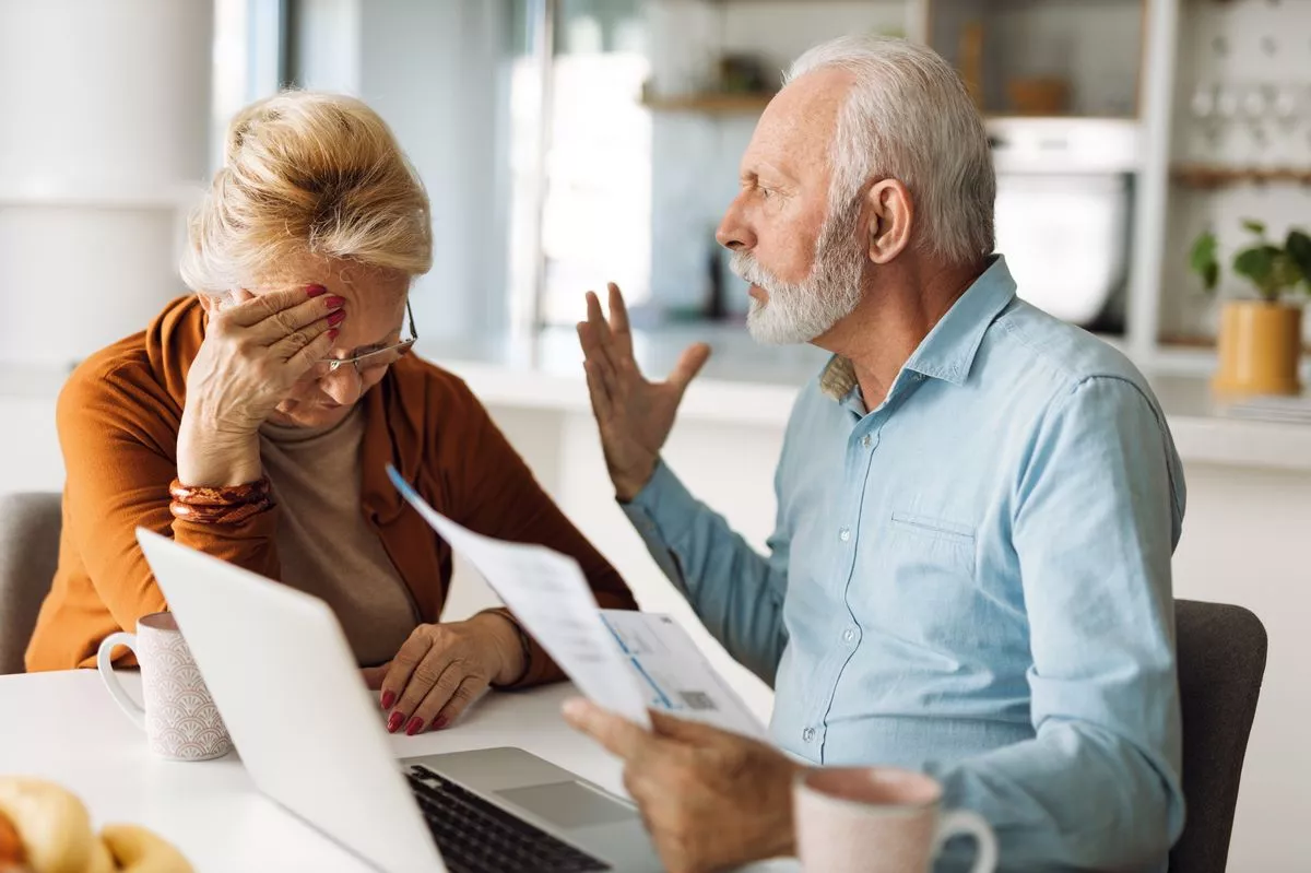 Frustrated man screaming at his wife while paying their bills over Internet at home