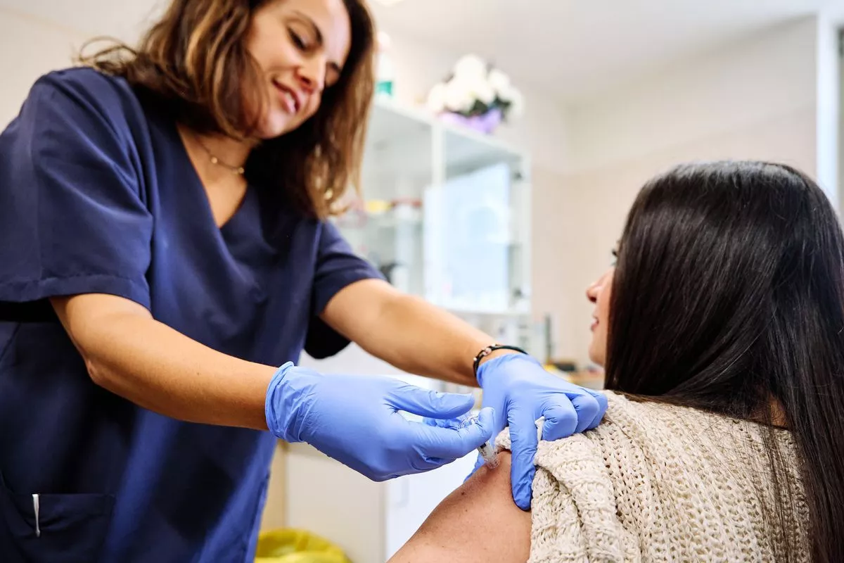 Rear view of a young woman receiving an injection for flu in an hospital