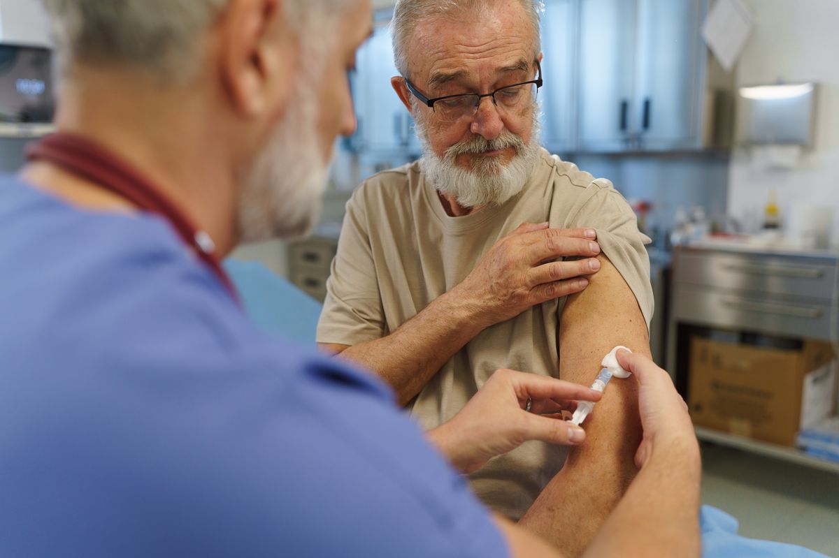 Doctor administering vaccine to older patient during preventive check-up