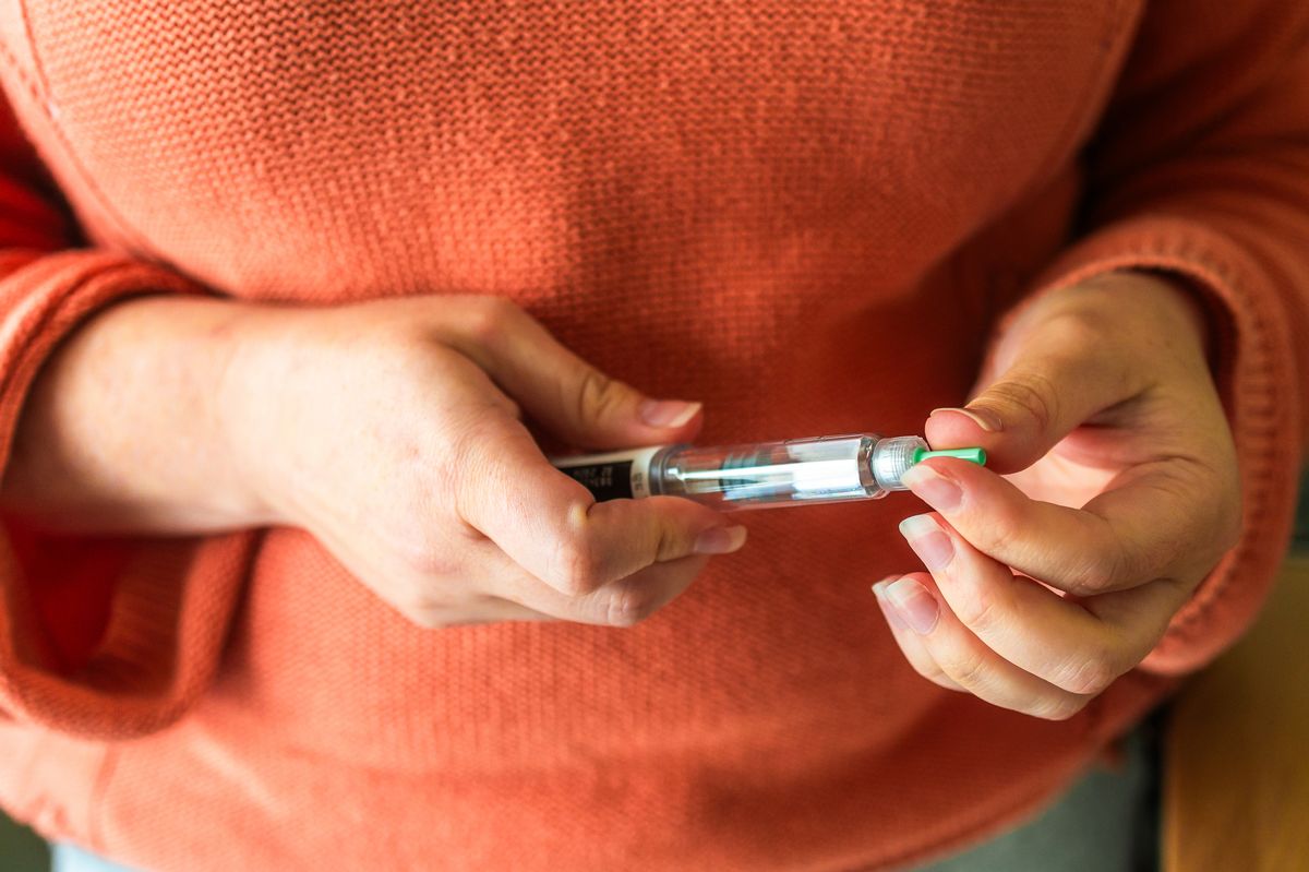 Close up of a woman's hands holding a weight loss injection syringe.