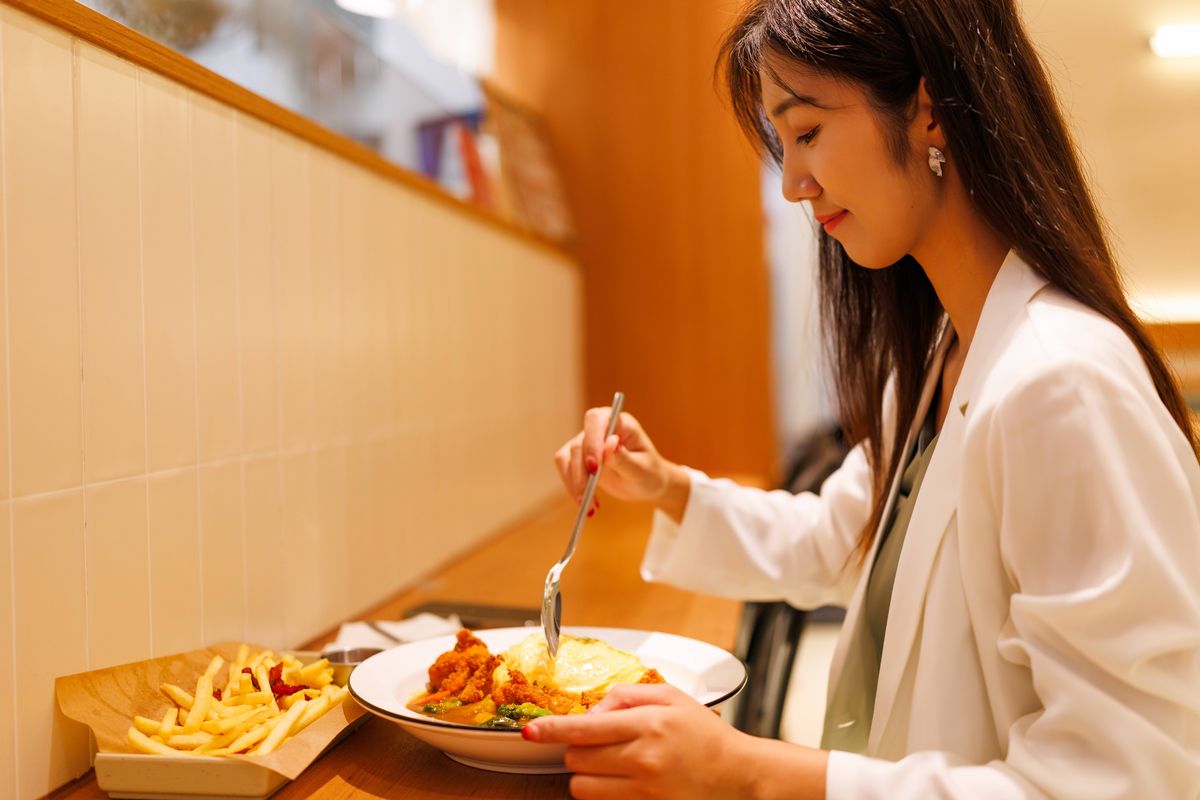 An Asian female professional is eating Japanese lunch, omelet rice, in a Japanese restaurant
