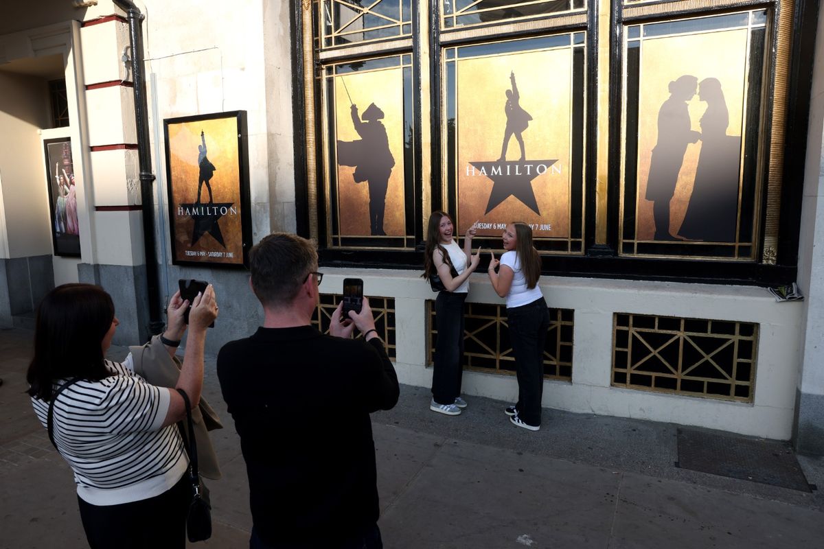 Excited fans get their photograph taken in front of the Hamilton posters at the Empire Theatre