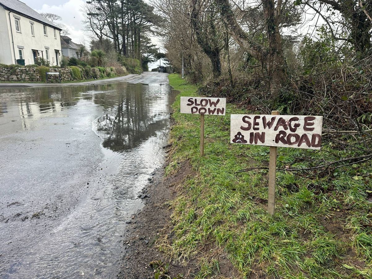 Signs put up by the side of Hendra Road in Stithians after a 'lake of poo' formed from overflowing raw sewage in the middle of the road