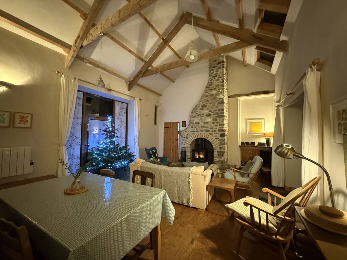 Inside the converted barn with log burner and exposed timber beams ay Under Starry Skies near Llandeilo