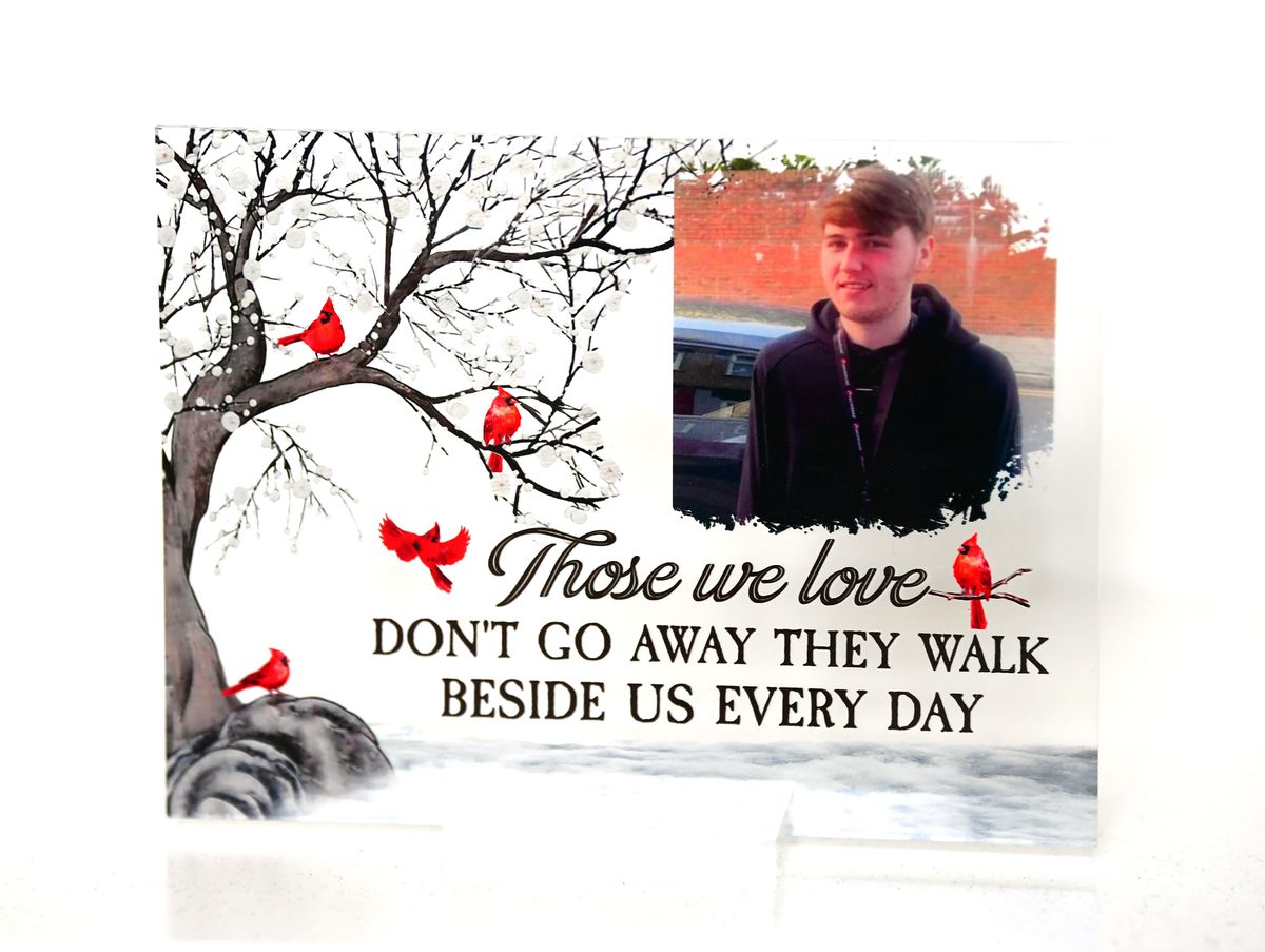 A photograph of Ellis Cox at his family home in Walton 18 months after he was shot dead. It shows Ellis on a white background and the words 'Those we love don't go away, they walk beside us every day'