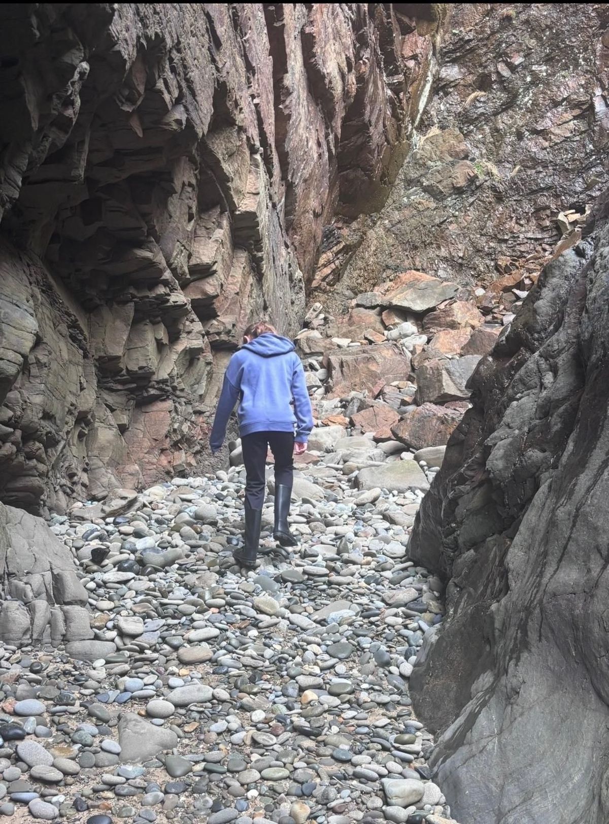 The back view of a little girl walking up a stony path, looking down