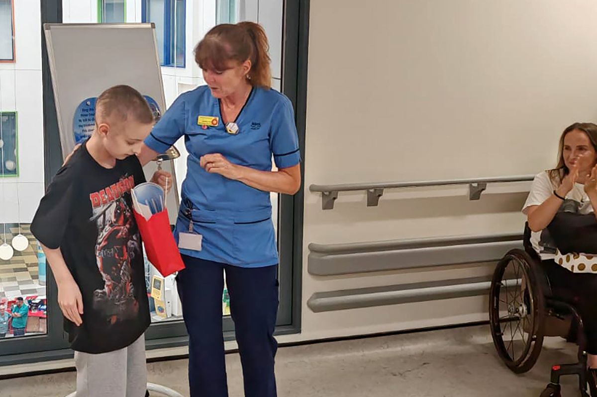 Andrew Muirhead rings the cancer bell with Nurse Angela Howat as mum Stephanie watches on