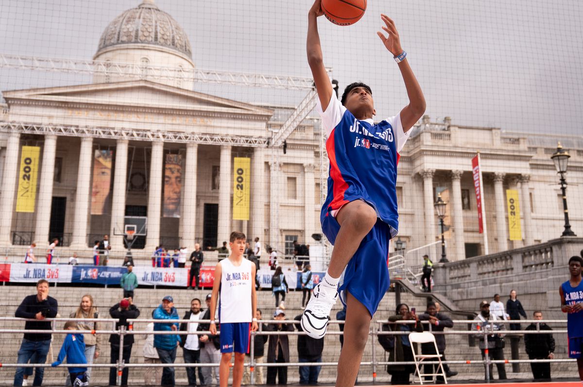A basketball player jumping up towards a hoop