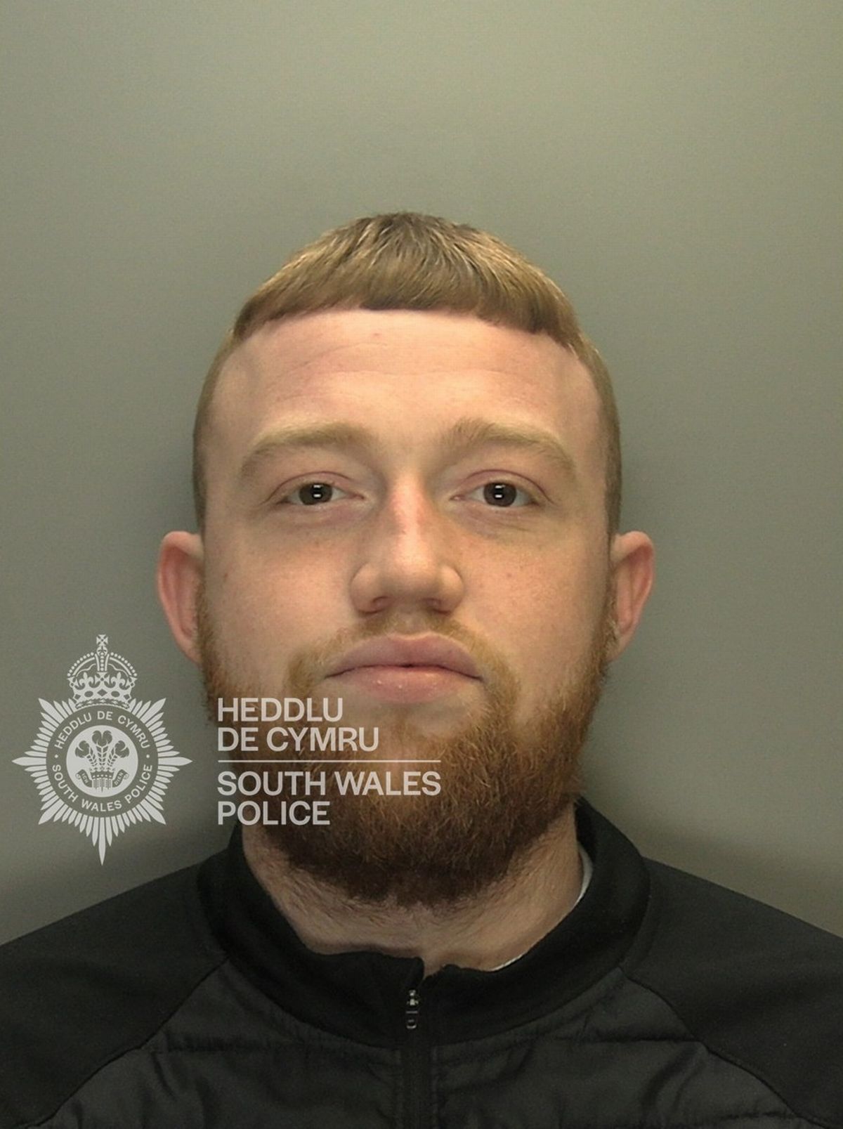 Custody photo of Brandon Down, 25, who has brown hair, a brown beard and is wearing a black jacket.