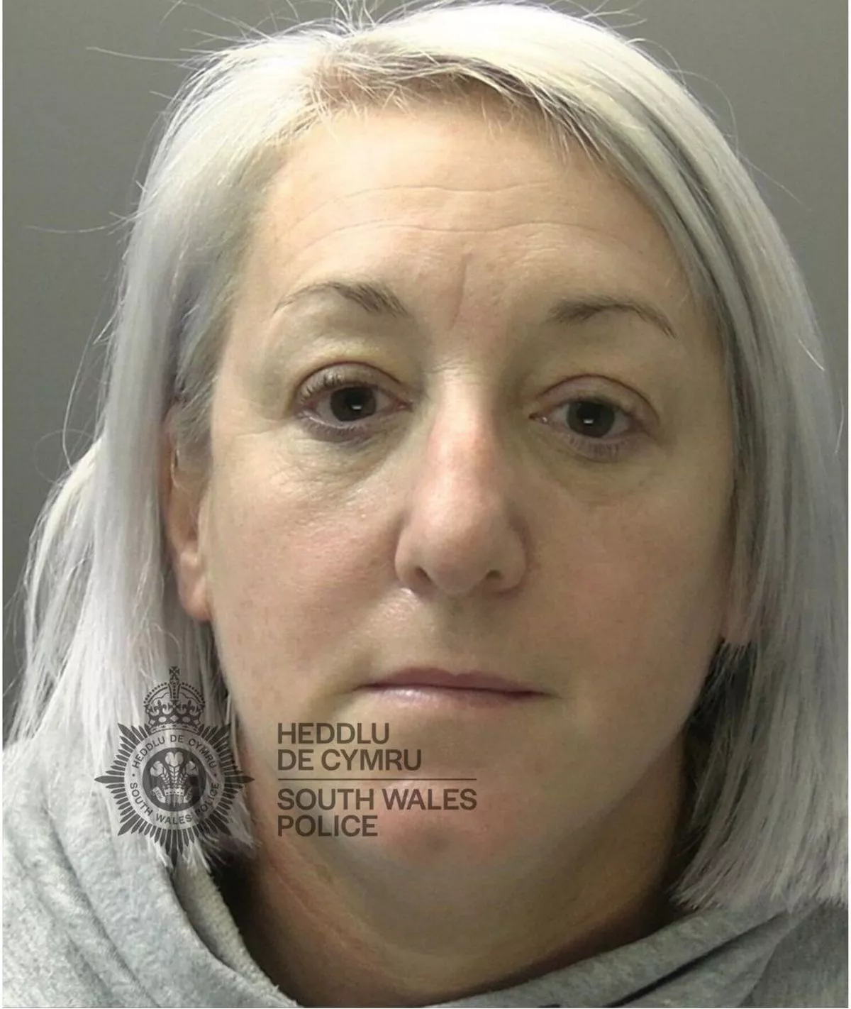 Custody photo of Kathryn MacDonald, 44, who has long grey hair and is wearing a grey hoody.