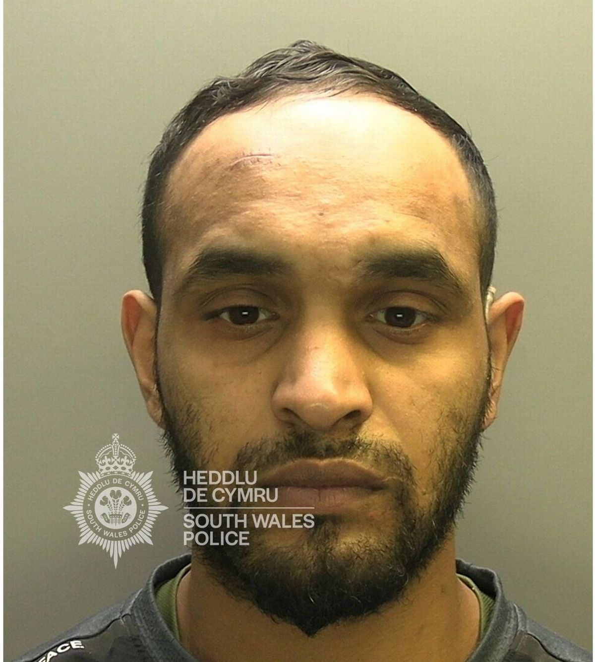 Custody photo of Kareem Abdo, 30, who has short black hair, a black beard and is wearing a grey shirt.