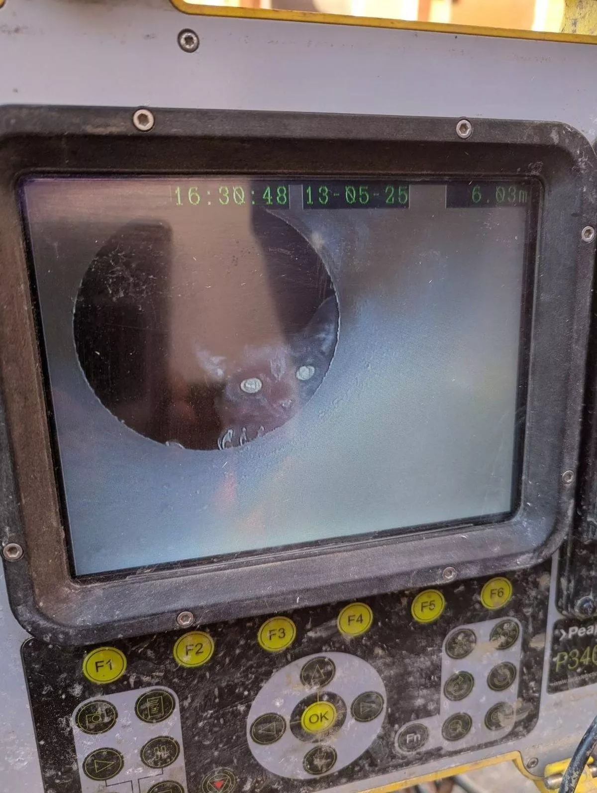 A close-up of an electronic device featuring a circular screen displaying a reflection, with a series of yellow buttons and a control panel in the foreground.