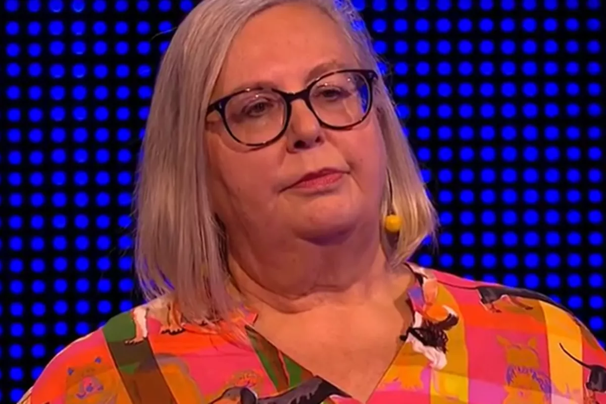 An image of a blonde woman with glasses and a colourful blouse.