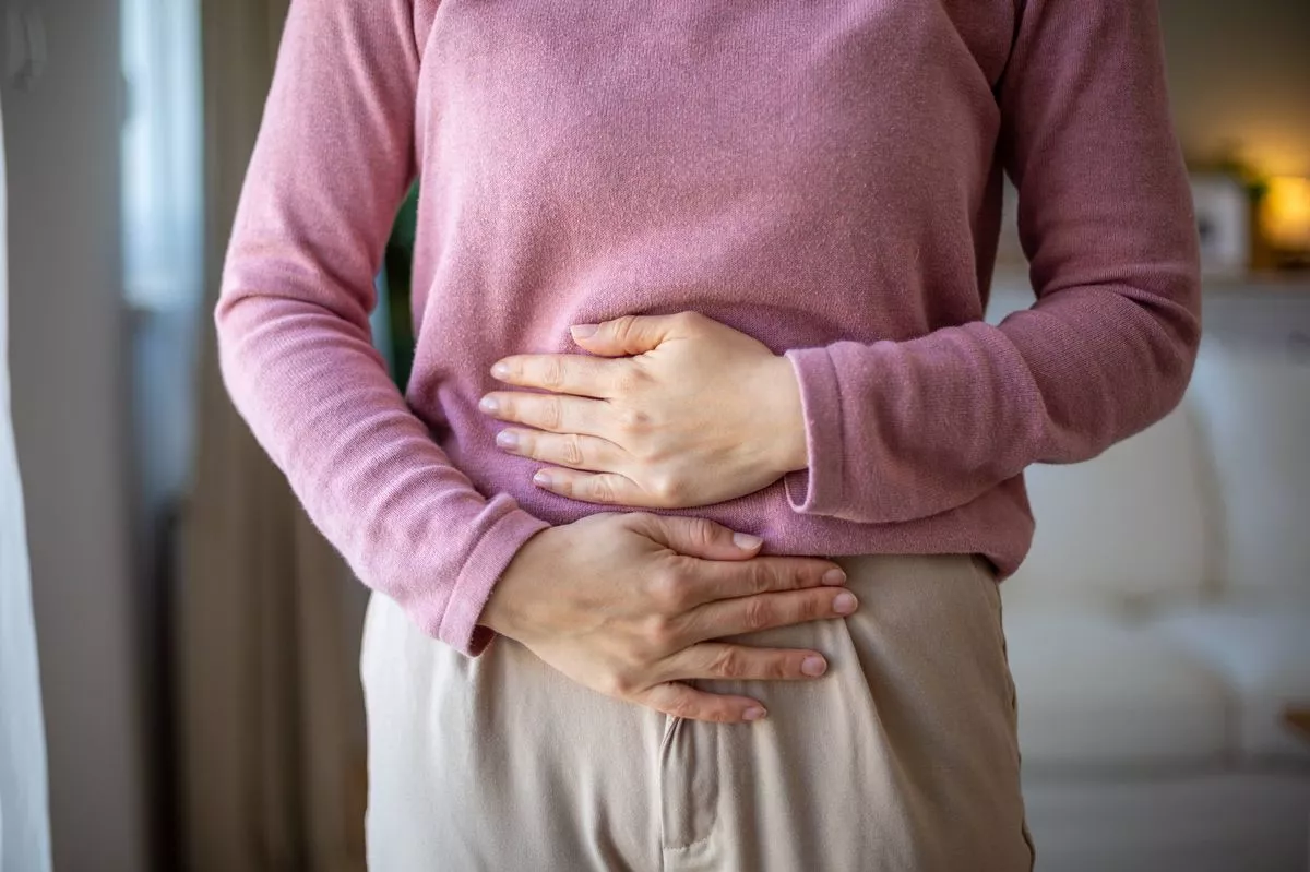 Mid adult woman holding her belly suffering from abdominal pain