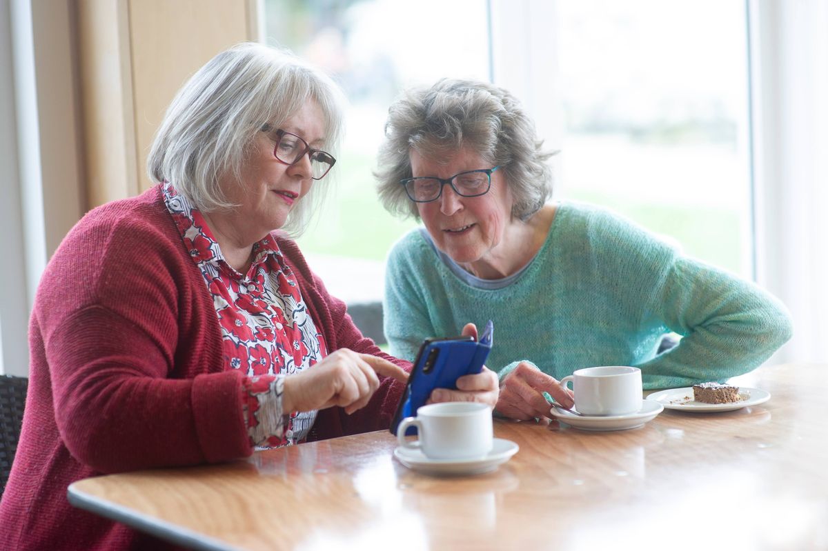 Two older women look at phone