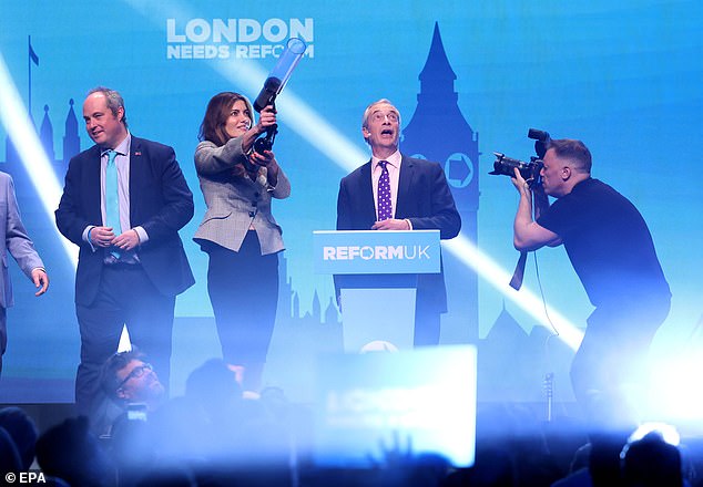 Ms Cunningham pictured firing t-shirts into the crowd at the rally as Mr Farage watches on. He also revealed Reform is ready to go to court next week to challenge Labour's attempts to postpone a string of local elections