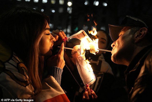 Protestors in London burn an image of Ayatollah Ali Khamenei during a rally held in solidarity with Iran's uprising, organised by The National Council of Resistance of Iran on January 11