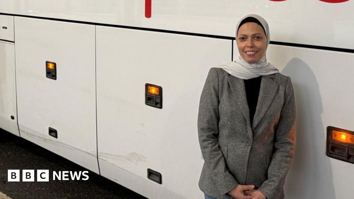 Fatima Benzbir wears a beige jacket, black top and white headscarf, as she leans casually against a coach.