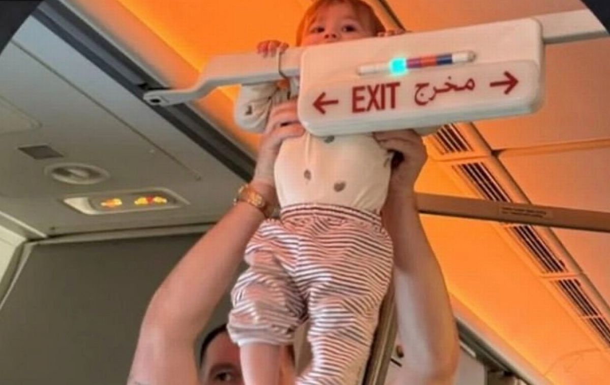 A baby being held up on an airplane 