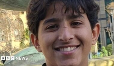 A teenage boy smiles in an outdoor setting.