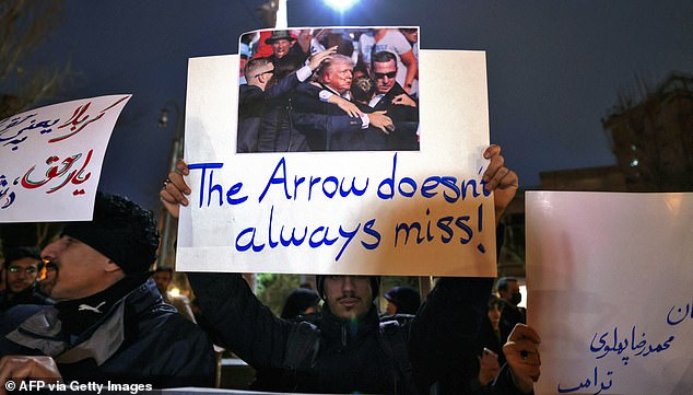 Members of the Basij volunteer Islamic militia hold placards during a protest in front of the British Embassy in Tehran on January 14, 2026. The Basij, linked to the Revolutionary Guards, are among the most devout supporters of the Islamic regime in Iran. A funeral ceremony was held on January 14 for over 100 members of the security forces and other "martyrs" killed in the demonstrations, which authorities have branded as "riots" while accusing protesters of waging "acts of terror". (Photo by ATTA KENARE / AFP via Getty Images)