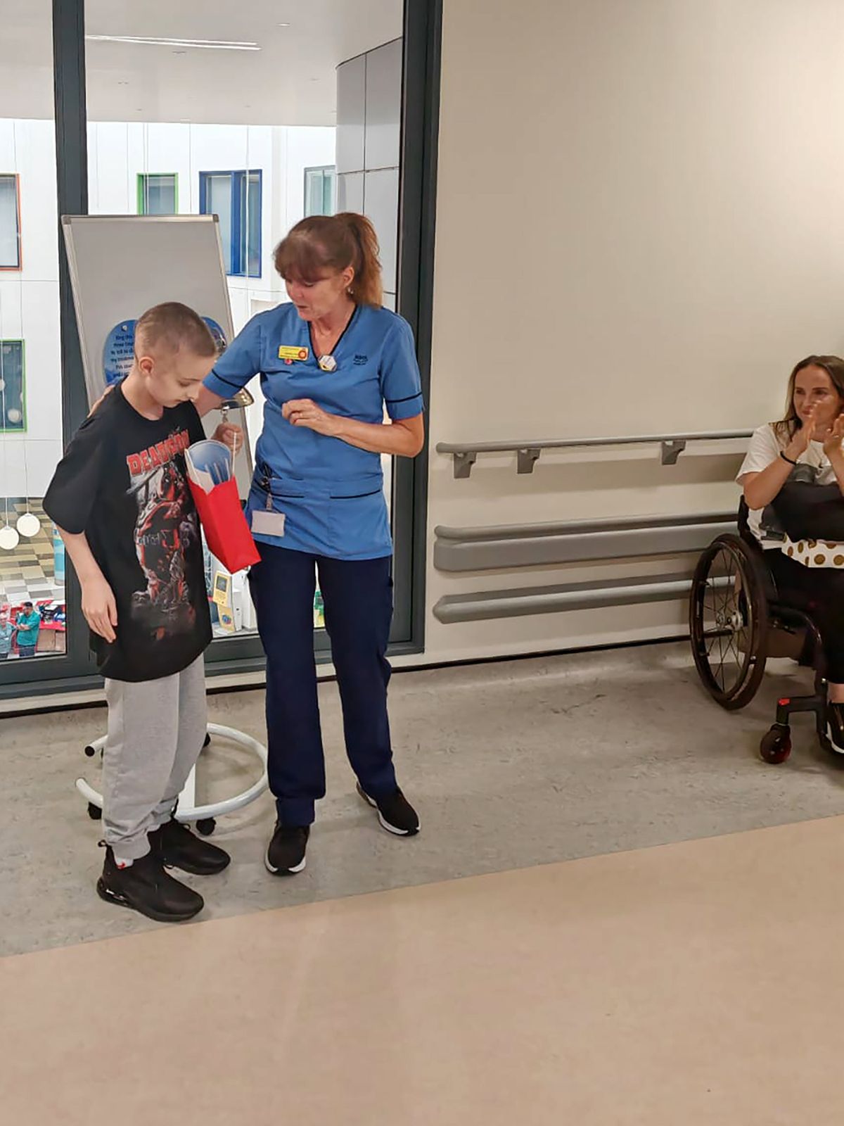 Andrew Muirhead rings the cancer bell with Nurse Angela Howat as mum Stephanie watches on