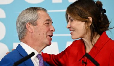 Laila Cunningham and Nigel Farage discussing current events at a business conference podium, engaging audience attention.