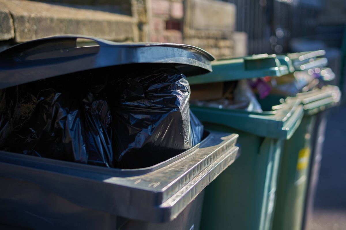 Gray and green garbage cans overfilled with domestic refuse