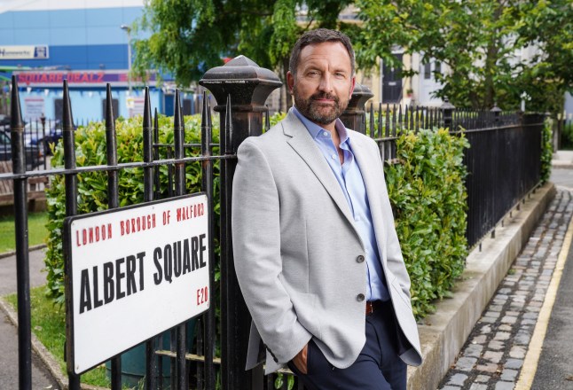 Jake Moon, posing against the Albert Square street sign in EastEnders