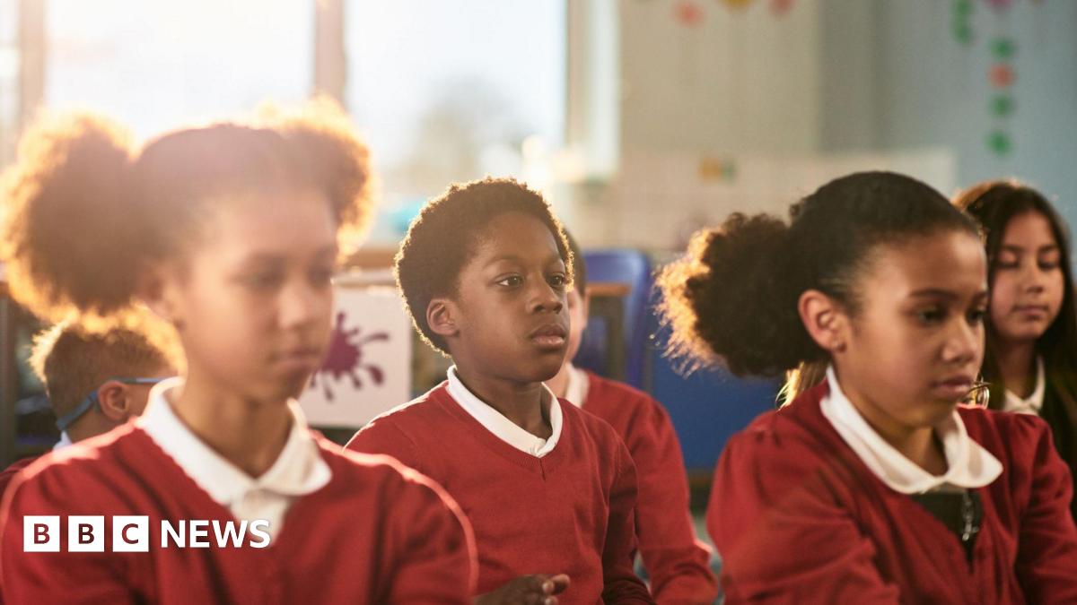 School children in red uniform preparing for relaxation session.