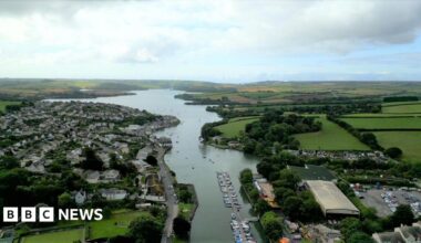 A picture of Kingsbridge taken from above, with an estuary in the centre. There is a number of properties either side of the water, plus green fields in the distance.