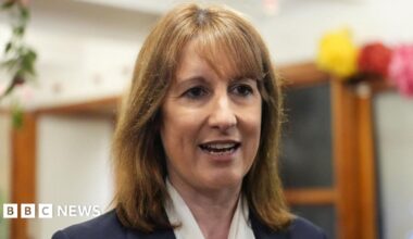 Prime Minister Mark Carney, wearing a black suit jacket, and a white button-up shirt leans his chin on his hands. He has short grey and black hair and is looking away from the camera.