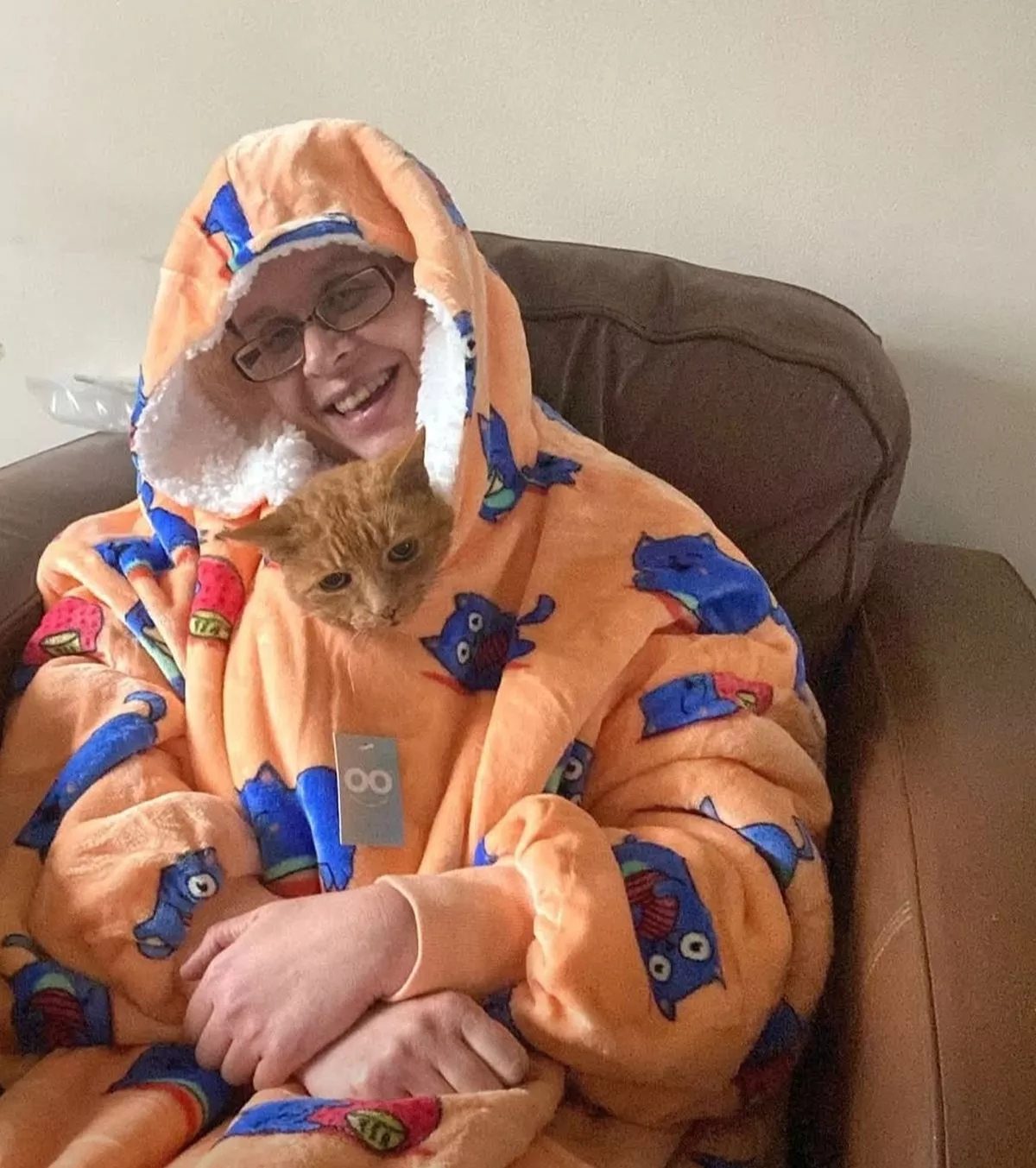 Clare sat wrapped up in a chair with a ginger cat