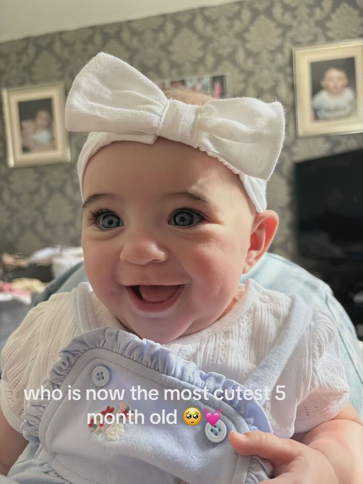 Hazel with a white bow on her head aged five months and smiling