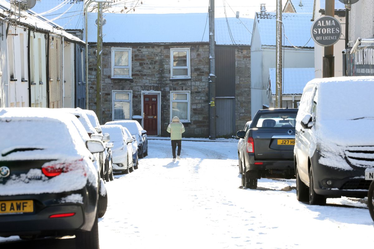 Man walking down a residential street covered in snow