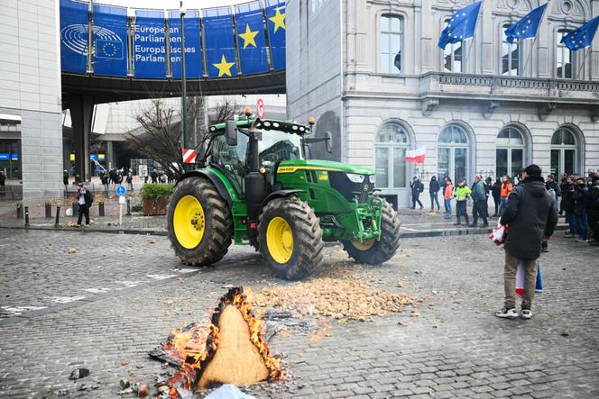 Farmers stand next to potatoes and a tractor parked in front of the European Parliament, during a farmers' protest to denounce agricultural reforms and trade agreements such as the Mercosur, in Brussels, on December 18, 2025.